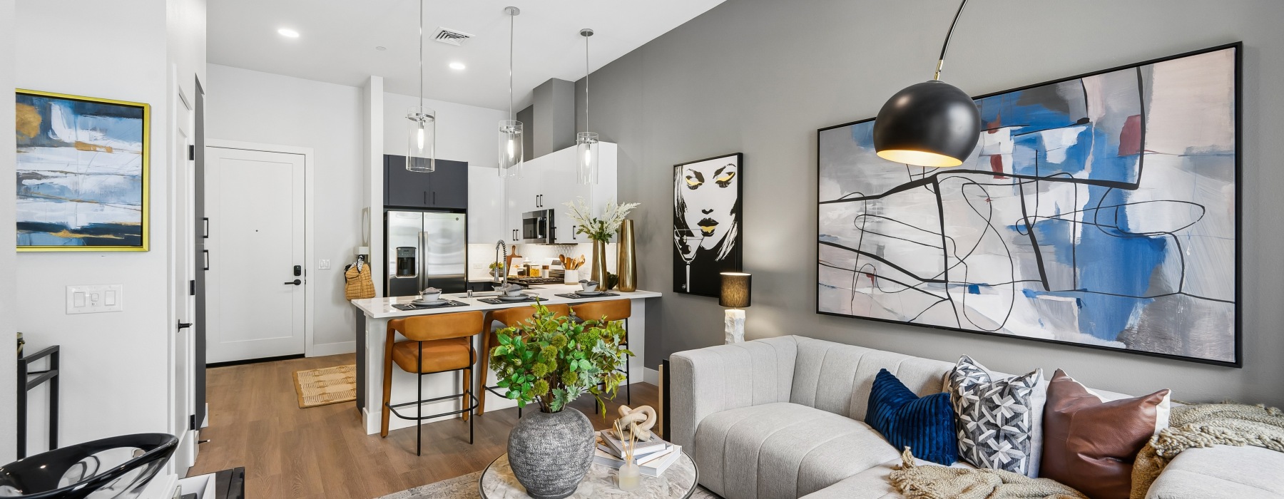 Modern one bedroom apartment at Bria in Symphony Park, Las Vegas, featuring an open-concept living room and kitchen, contemporary furnishings, high ceilings, and upscale finishes.